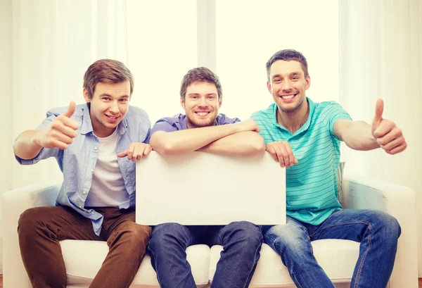 Smiling male friends holding white blank board — Stock Photo, Image