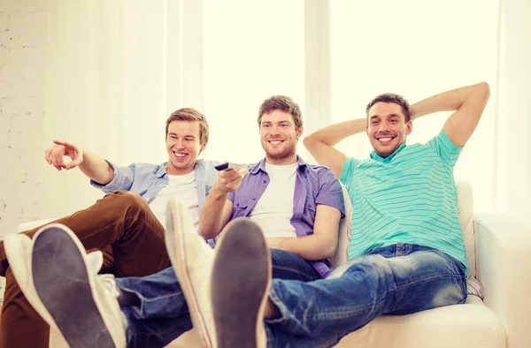 Amigos sonrientes con control remoto en casa —  Fotos de Stock