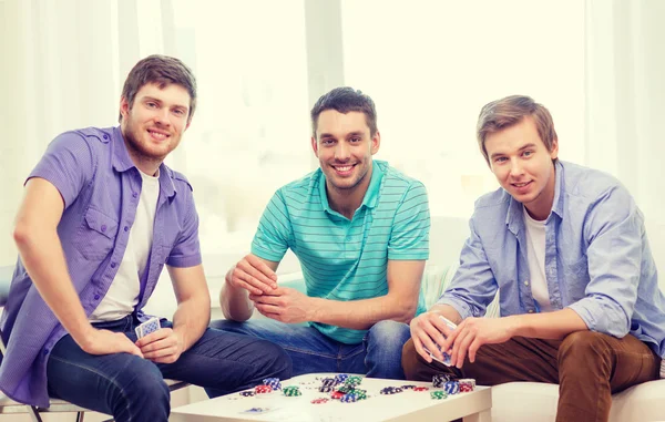 Feliz tres amigos masculinos jugando póquer en casa — Foto de Stock