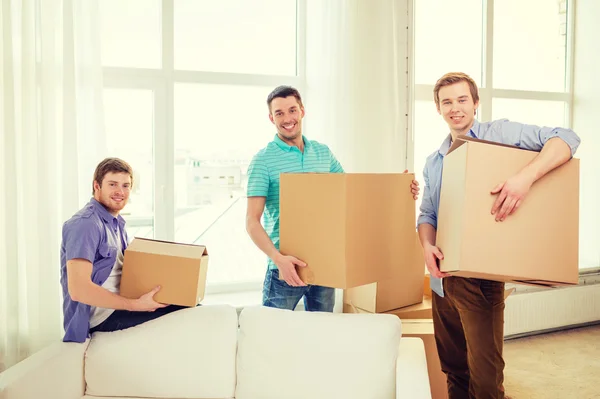 Sorridente masculino amigos carregando caixas no novo lugar — Fotografia de Stock