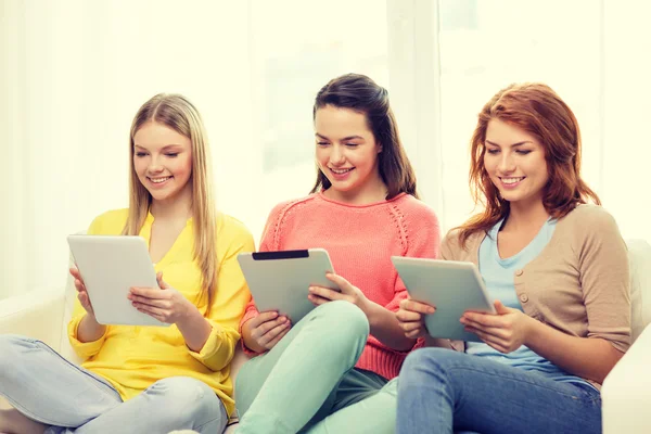 Drie lachende tienermeisjes met tablet pc thuis — Stockfoto