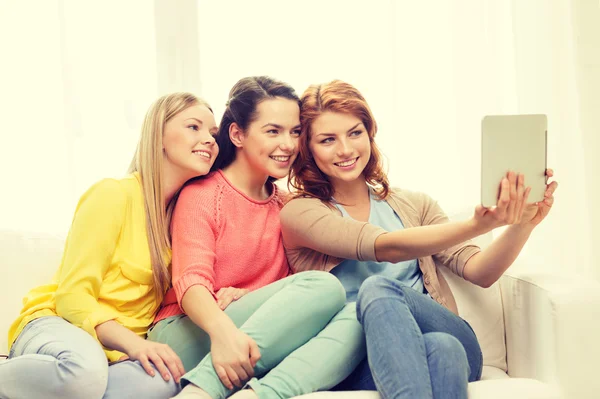 Drie lachende tienermeisjes met tablet pc thuis — Stockfoto