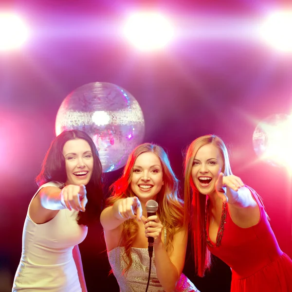 Tres mujeres sonrientes bailando y cantando karaoke — Foto de Stock