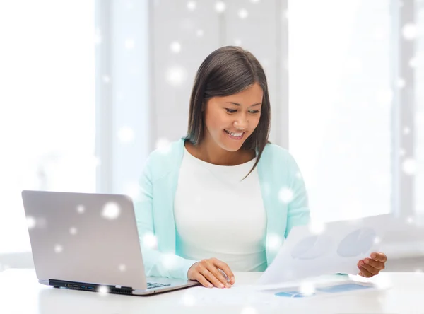Lächelnde junge Frau mit Laptop und Papieren — Stockfoto