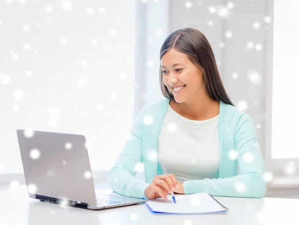 Lächelnde junge Frau mit Laptop und Notizbuch — Stockfoto