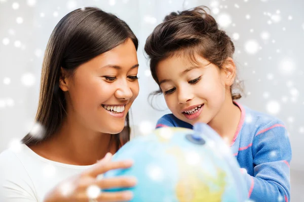 Mother and daughter with globe indoors — Stock Photo, Image