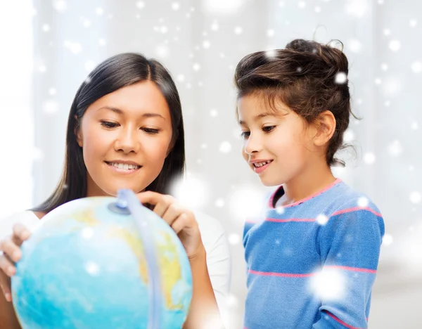 Mãe e filha com globo dentro de casa — Fotografia de Stock