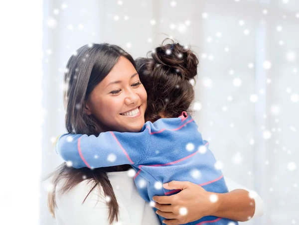 Sonriente niña y madre abrazándose en el interior —  Fotos de Stock