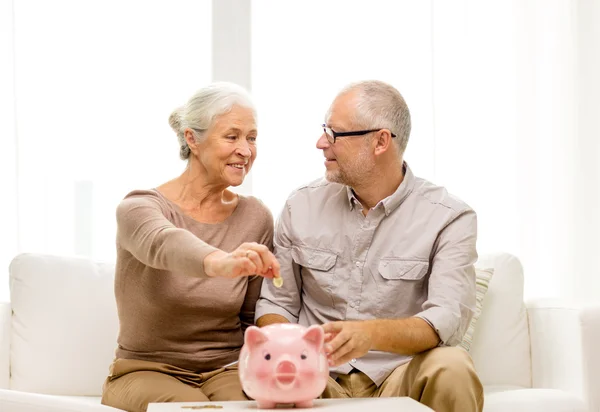 Senior par med penge og sparegris derhjemme - Stock-foto