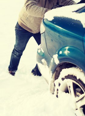 closeup of man pushing car stuck in snow clipart