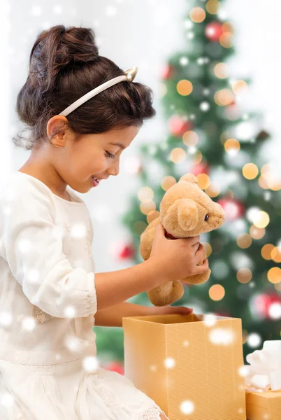 Smiling little girl with gift box and teddy bear — Stock Photo, Image