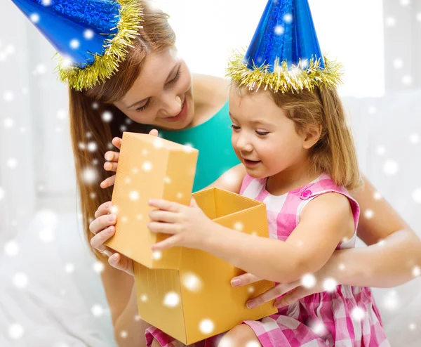 Madre e hija en sombreros de fiesta con caja de regalo —  Fotos de Stock