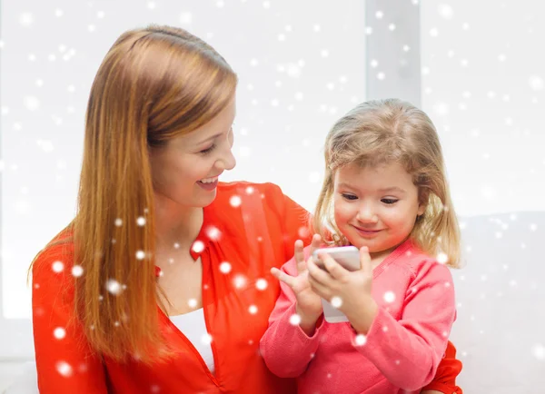 Mãe feliz e filha com smartphone em casa — Fotografia de Stock