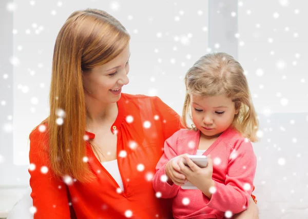 Mãe feliz e filha com smartphone em casa — Fotografia de Stock