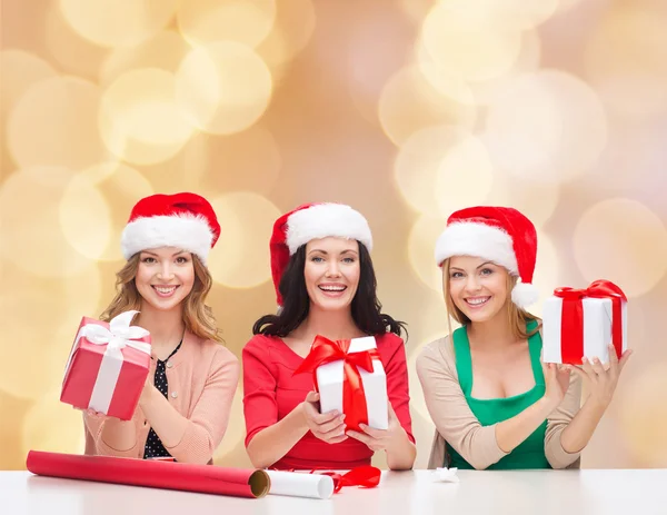 Lachende vrouw in santa helper hoeden verpakking geschenken — Stockfoto