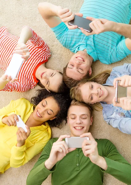 Group of smiling people lying down on floor — Stock Photo, Image