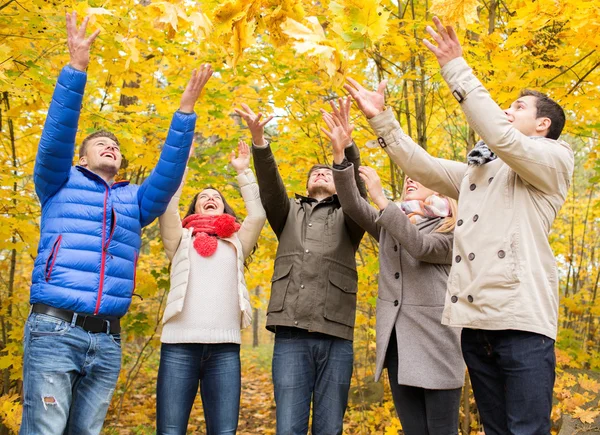 Grupo de hombres y mujeres sonrientes en el parque de otoño — Foto de Stock