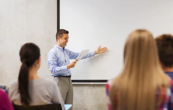 Grupp studenter och leende lärare med anteckningsblock — Stockfoto