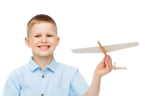 Menino sorrindo segurando um modelo de avião de madeira — Fotografia de Stock