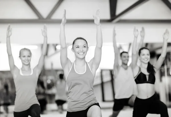 Grupo de personas sonrientes haciendo ejercicio en el gimnasio — Foto de Stock
