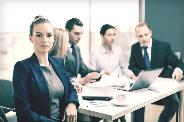 Femme d'affaires au bureau avec l'équipe sur le dos — Photo