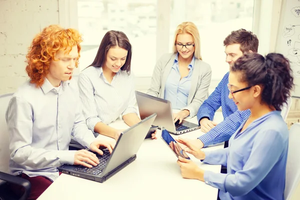 Squadra sorridente con computer portatili e da tavolo — Foto Stock