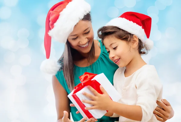 Felice madre e ragazza in cappelli di Babbo Natale con confezione regalo — Foto Stock