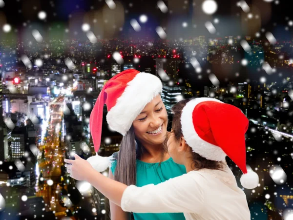 Happy mother and girl in santa hats — Stock Photo, Image