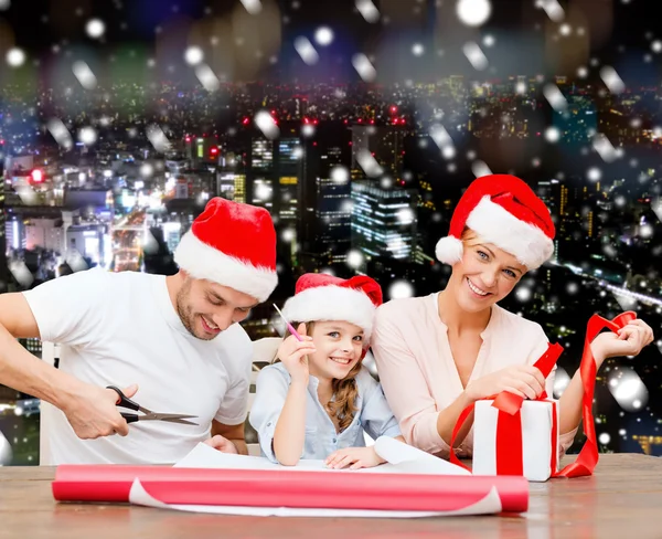 Gelukkige familie in santa helper hoeden cadeau verpakking — Stockfoto