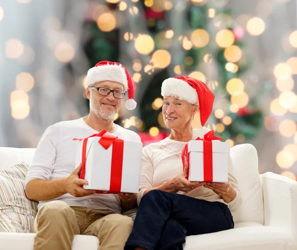 Feliz pareja de ancianos en sombreros de santa con cajas de regalo — Foto de Stock