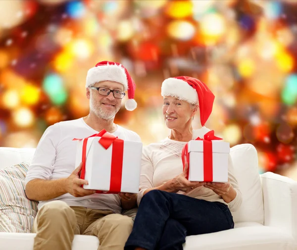 Feliz casal sênior em chapéus de santa com caixas de presente — Fotografia de Stock