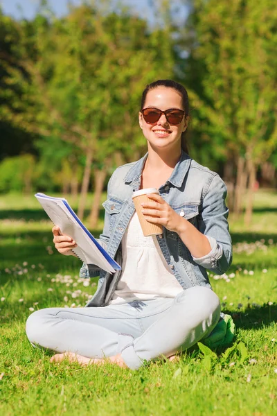 Leende ung flicka med anteckningsboken och kaffe kopp — Stockfoto