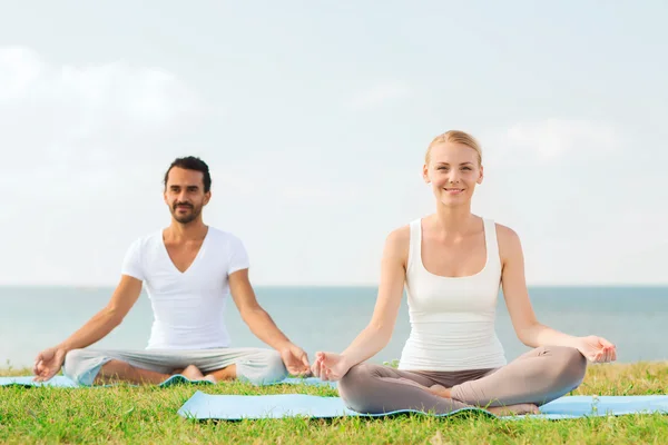 Coppia sorridente fare esercizi di yoga all'aperto — Foto Stock