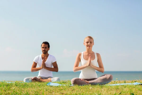 Çift gülümseyen açık havada yapım yoga egzersizleri — Stok fotoğraf