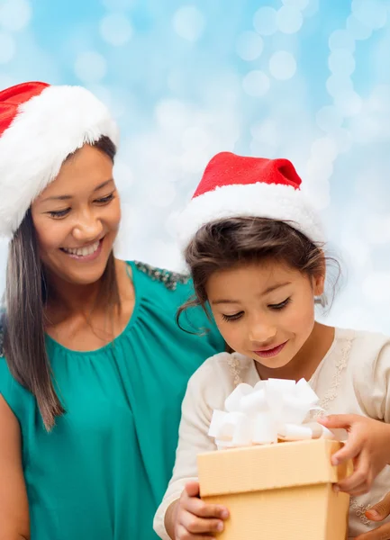 幸福的母亲和女孩在圣诞老人的帽子与礼品盒 免版税图库照片