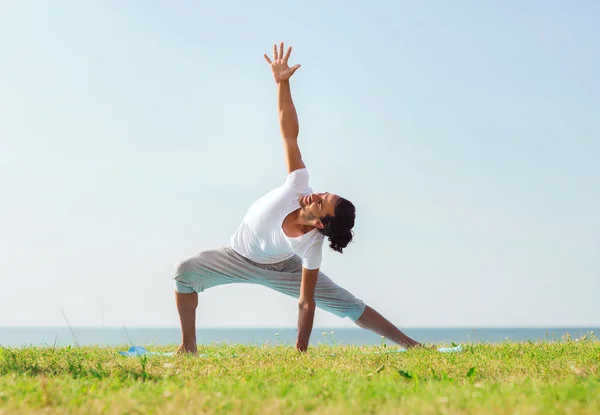 Leende mannen att göra yoga övningar utomhus — Stockfoto