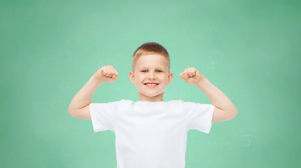 Щасливий маленький хлопчик у білій футболці згинає біцепси — стокове фото