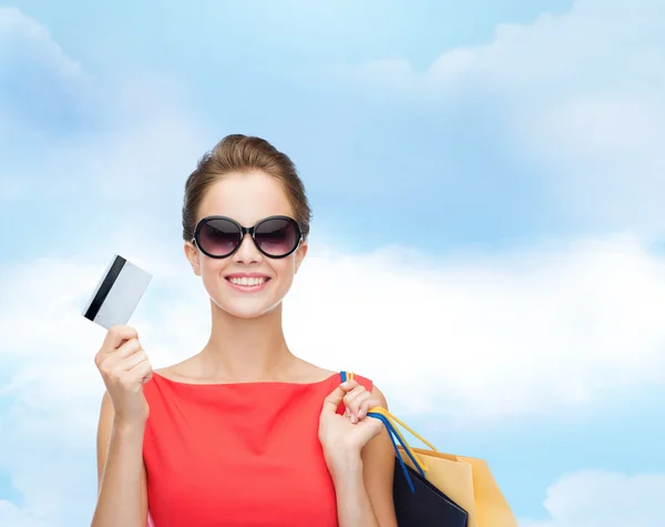 Mujer sonriente con bolsas de compras y tarjeta de plástico — Foto de Stock