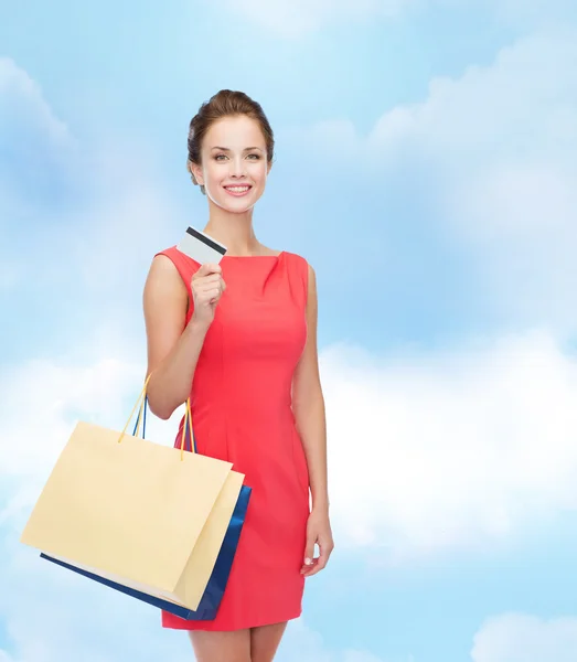 Leende kvinna med shoppingväskor och plastkort — Stockfoto