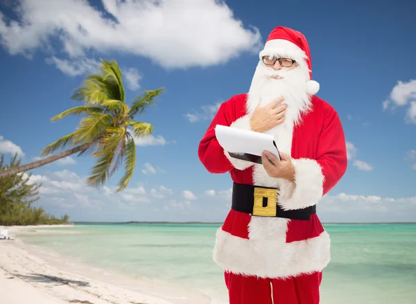 Человек в костюме Санта-Клауса с блокнотом — стоковое фото