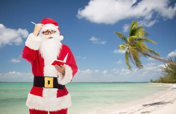 Man in costume of santa claus with notepad — Stock Photo, Image