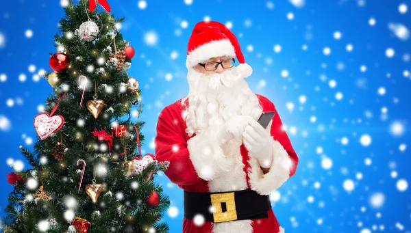 Santa claus with smartphone and christmas tree — Stock Photo, Image