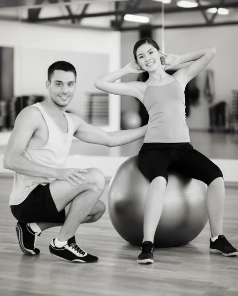 Treinador masculino com mulher fazendo crunches na bola — Fotografia de Stock