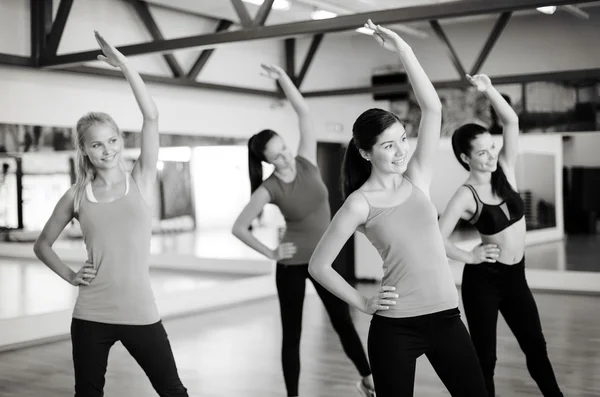 Groep glimlachende mensen die zich uitstrekt in de sportschool — Stockfoto