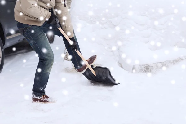 Nahaufnahme eines Mannes, der mit Schaufel neben Auto Schnee schaufelt — Stockfoto