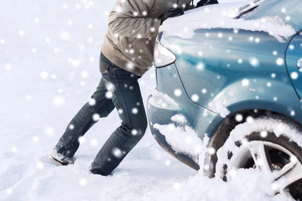 Gros plan de l'homme poussant la voiture coincée dans la neige — Photo