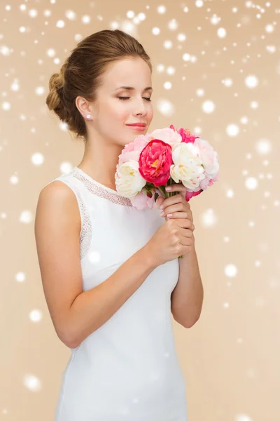 Femme souriante en robe blanche avec un bouquet de fleurs — Photo