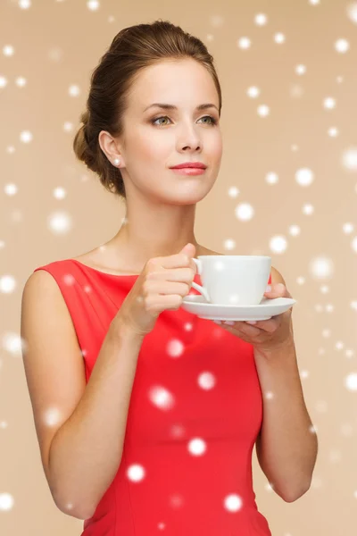Lachende vrouw in rode jurk met kop koffie — Stockfoto