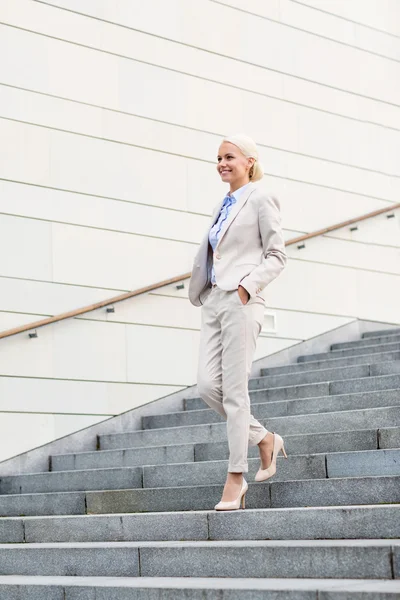 Молодая улыбающаяся деловая женщина спускается по лестнице — стоковое фото