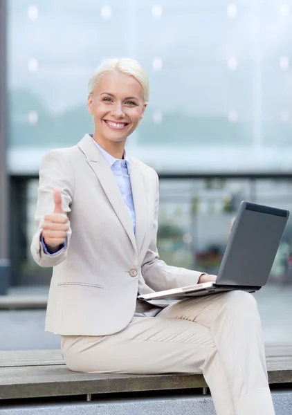 Glimlachende zakenvrouw werken met laptop buiten — Stockfoto